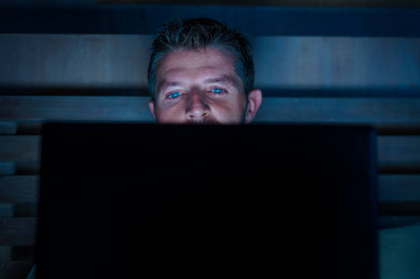 A man alone at a screen in a darkened room